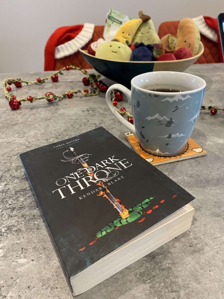 One Dark Throne on a coffee table with a Christmas coffee mug